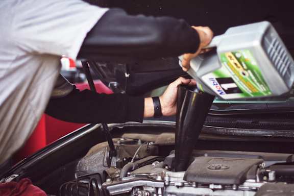 A person is pouring oil into a car engine.