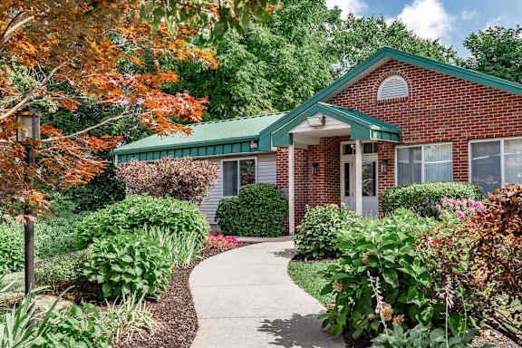 A red brick house with a green roof and a white door.
