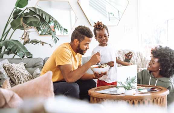 A young girl is laughing while looking at a tablet with a man beside her.