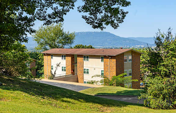 A building with a brown roof is surrounded by greenery and trees.