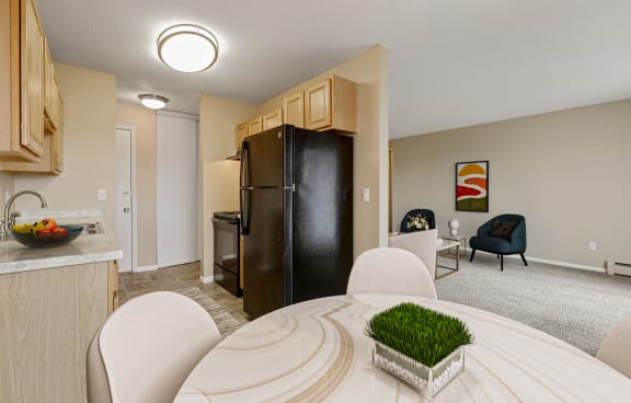 a living room with a dining room table and a kitchen with a refrigerator