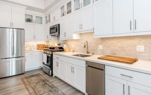 A kitchen with white cabinets and a black refrigerator.