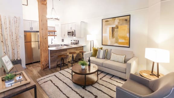 a living area with a couch coffee table and a kitchen in the background