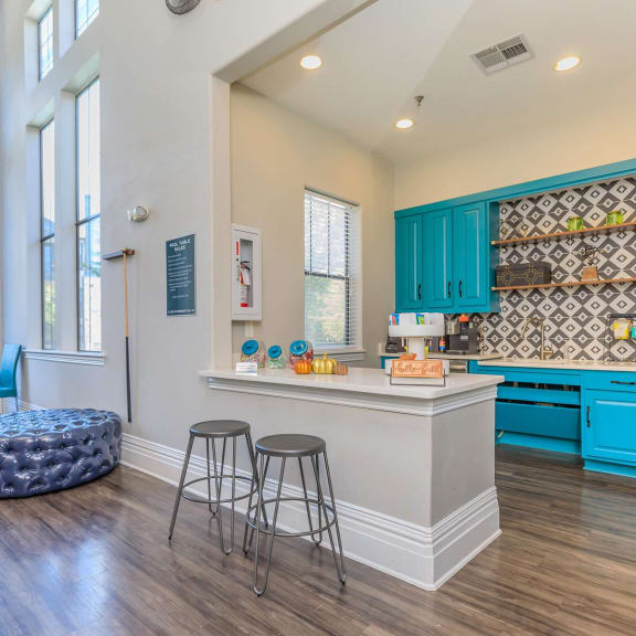 a kitchen with blue cabinets and a counter with three stools