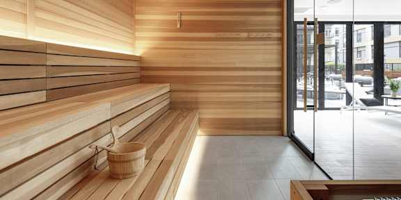 A wooden sauna room with a glass door leading to a balcony.