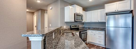 A kitchen with granite countertops and stainless steel appliances.