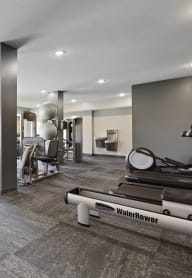 A gym with a row of treadmills and a row of stationary bikes at Sonder Point 50+ Apartments, Brooklyn Center, MN, 55430