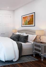 A bedroom with a large bed and two paintings on the wall.