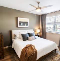 a bedroom with a large white bed and a ceiling fan at Woodlands Creekside Apartments, Georgia, 30253