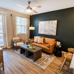 A living room with a brown sofa, a coffee table, and a ceiling fan. at Woodlands Creekside Apartments, Georgia, 30253