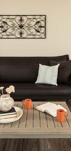 A living room with a black couch, a grey coffee table, and a lamp.