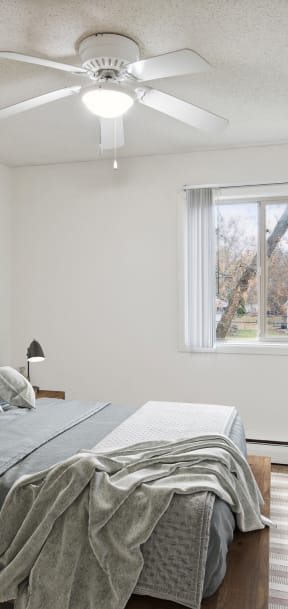 A bedroom with a bed, a ceiling fan, and a painting on the wall. at Minnehaha Manor, Oakdale, 55128