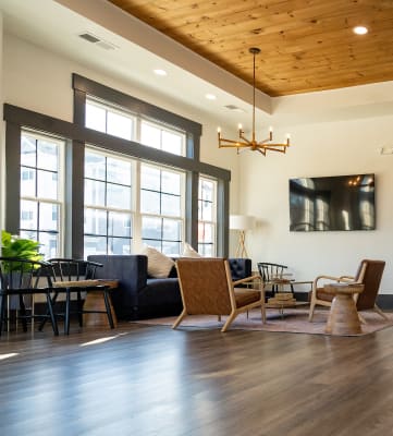 a living room with a couch chairs and a tv on the wall