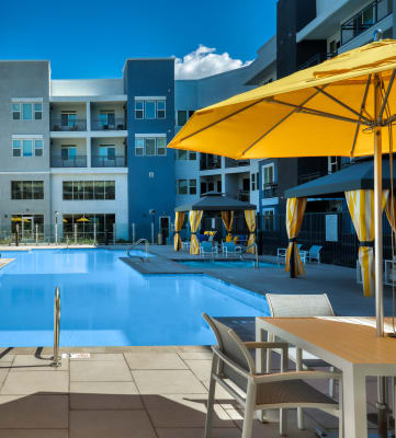 a swimming pool with yellow umbrellas and white tables and chairs