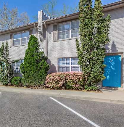 A parking lot in front of a grey building with blue doors.