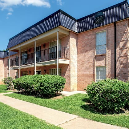 A brick building with a black roof and a green lawn in front.