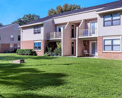 an apartment building with green grass in front of it