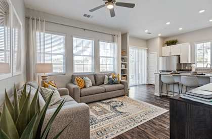 A living room with a couch, a rug, and a ceiling fan.