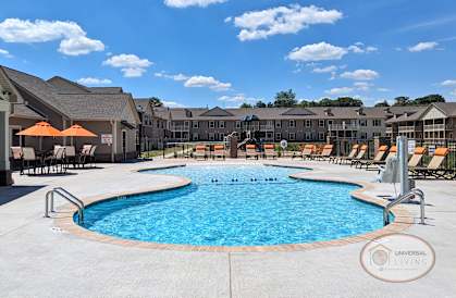 a swimming pool with chairs and umbrellas in front of a building