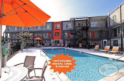 a pool with an orange umbrella next to an apartment building