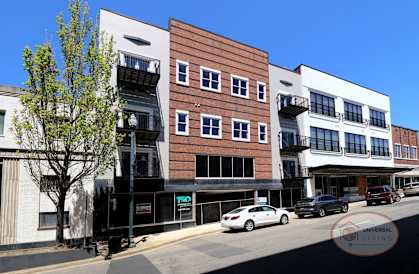 A white car is parked on the street in front of a building with a sign that says "UNIVERSAL LIVING".