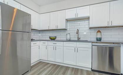 A kitchen with white cabinets and a stainless steel refrigerator.at Solara, Phoenix