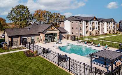 an outdoor pool with lounge chairs in front of an apartment building