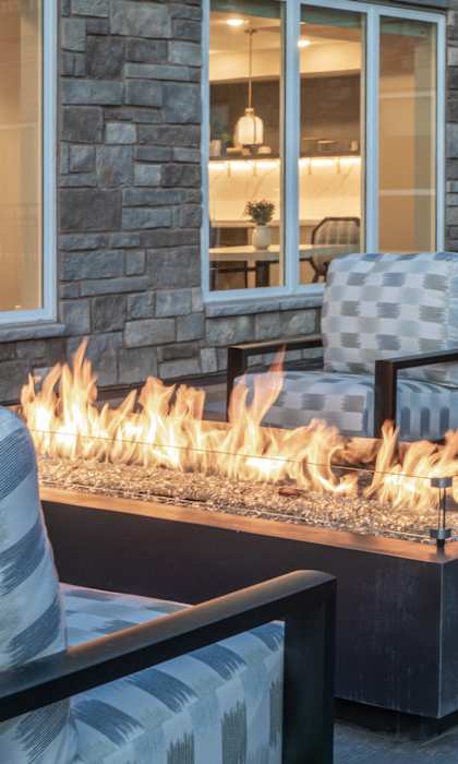 A patio with a fire pit and chairs.