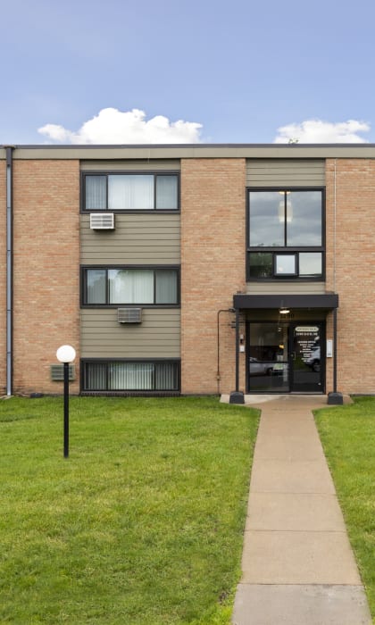 A building with a grey roof and a green lawn in front. at Northeast Villas, Fridley, 55421