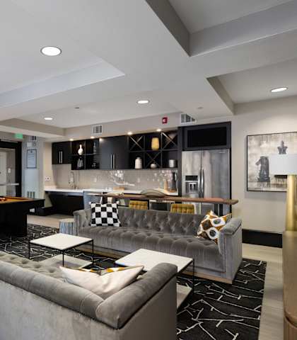 A modern living room with a pool table and a grey sofa.