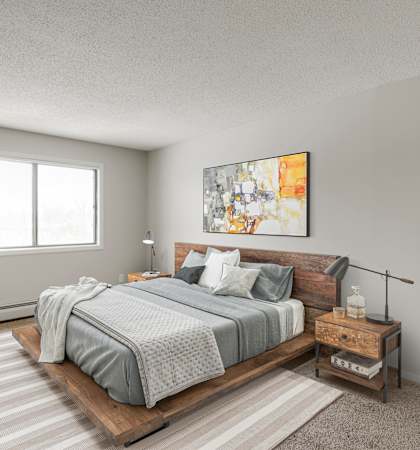 A bedroom with a bed, nightstand, and a plant.