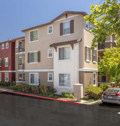 A parking lot in front of a multi-story apartment building.