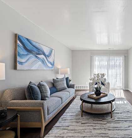 A living room with a grey couch, a coffee table, and a painting on the wall.