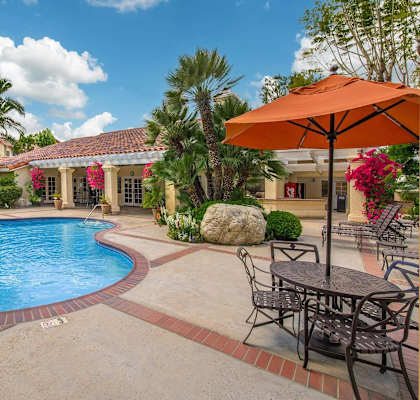 a backyard swimming pool with patio furniture and umbrellas at Victoria Springs Apartments, California, 92504