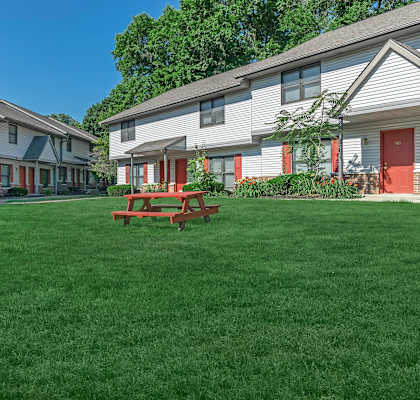 A grassy area in front of a building with a picnic table.