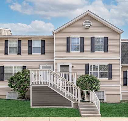 A two-story house with a staircase leading to the front door.