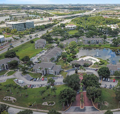 an aerial view of a city with a pond and buildings