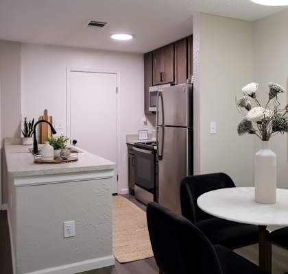 a dining area with a small white table and four black chairs