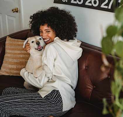 a woman sitting on a couch holding a dog