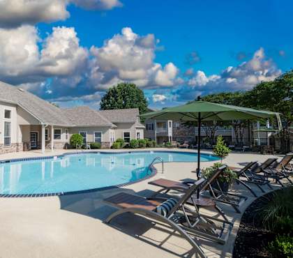 A large swimming pool surrounded by lounge chairs and umbrellas.
