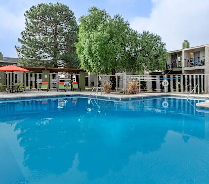 A swimming pool in front of a building with a fence around it.