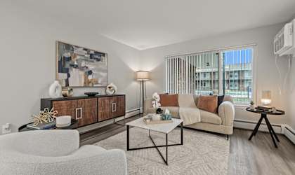 A modern living room with a white sofa, a coffee table, and a large painting on the wall.