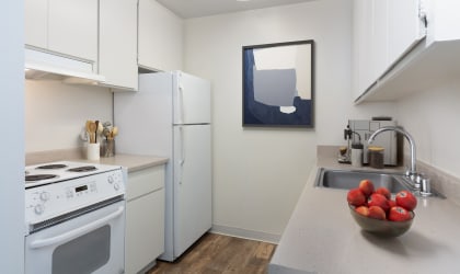 a kitchen with white appliances and a bowl of fruit on the counter