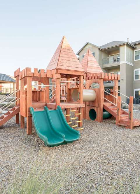 a playground with a set of slides in front of an apartment building at Cypress Creek at Hazelwood Street, Princeton, TX
