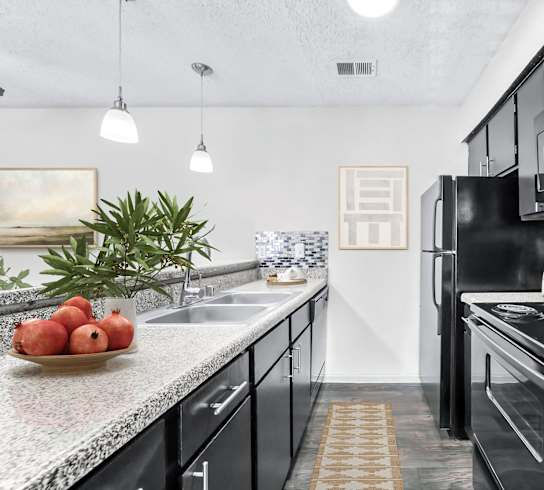 an apartment kitchen with black appliances and granite counter tops  at Vesper, Dallas, 75254