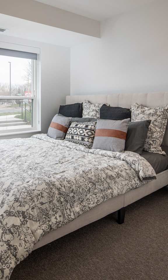 A bedroom with a large bed and a nightstand with a lamp.