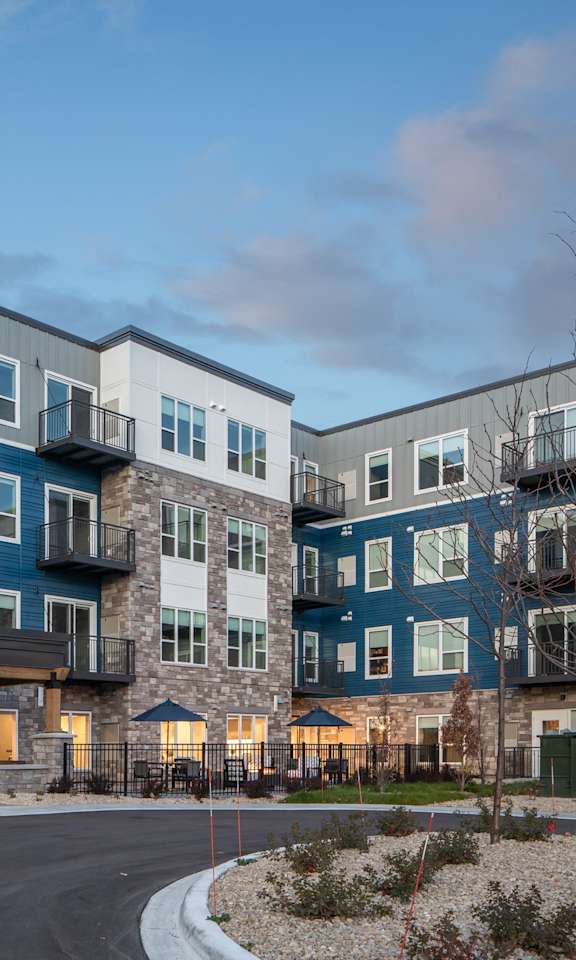 The image shows the exterior of Oakdale Commons apartment building at dusk.