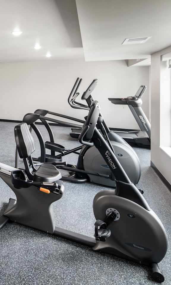 A spacious gym with a variety of equipment including treadmills, elliptical machines, and weights.