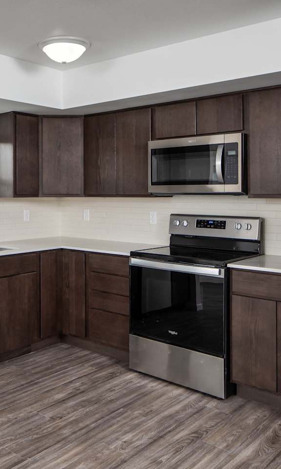 A kitchen with dark brown cabinets and stainless steel appliances.