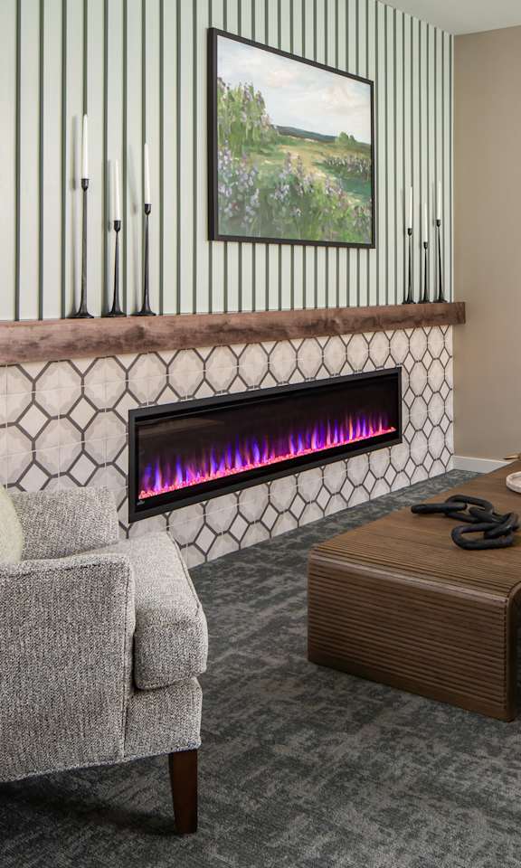 A grey chair is in front of a fireplace in a room.